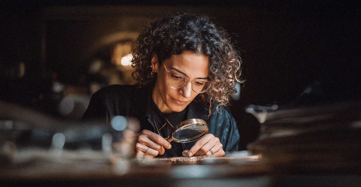 Vrouw die sieraden beoordeelt met een loep aan een bureau